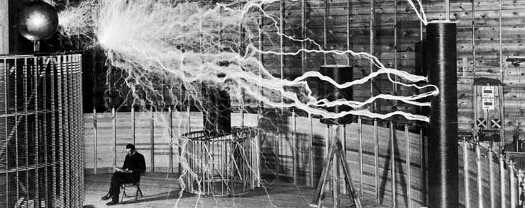 Nikola Tesla sitting in front of his magnetic generator