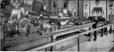 1894 engraving, fig. 297, printed p. 478: Long table of motors, rings and coils at the World's Fair exhibit, railing in front, 'Electrical Engineer' credit lower right